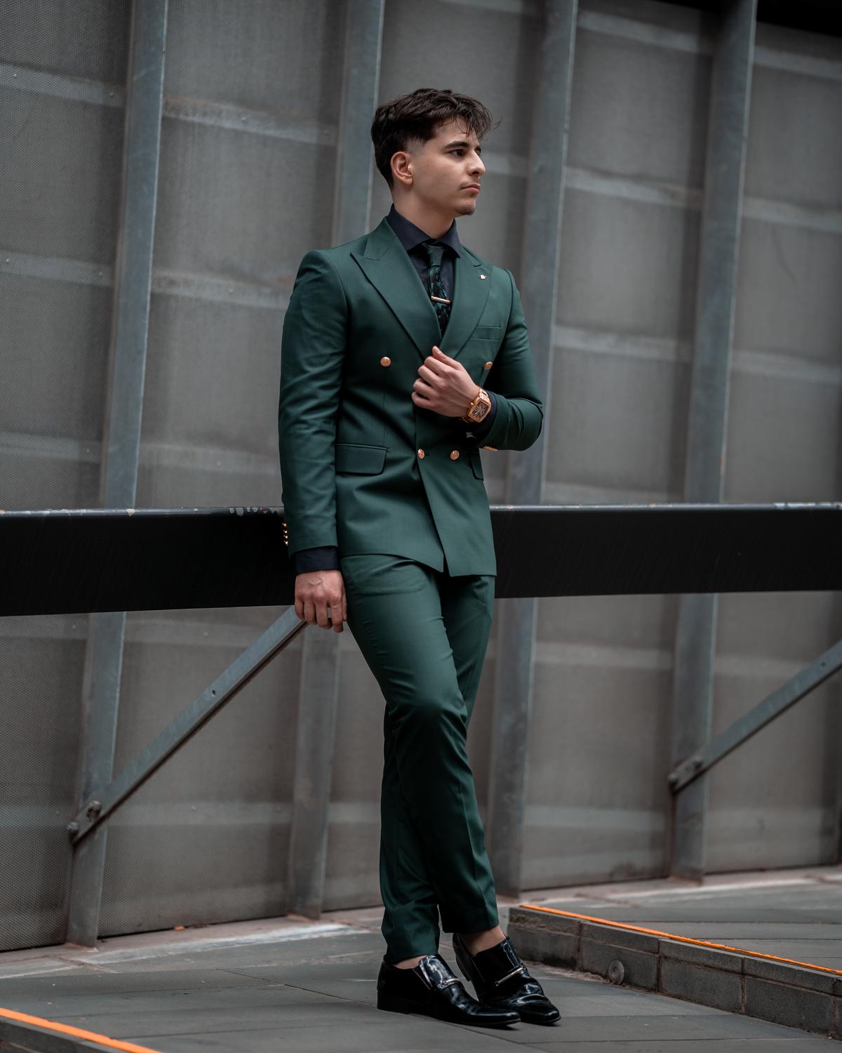Mohsen Carter leaning on a rail in a green suit